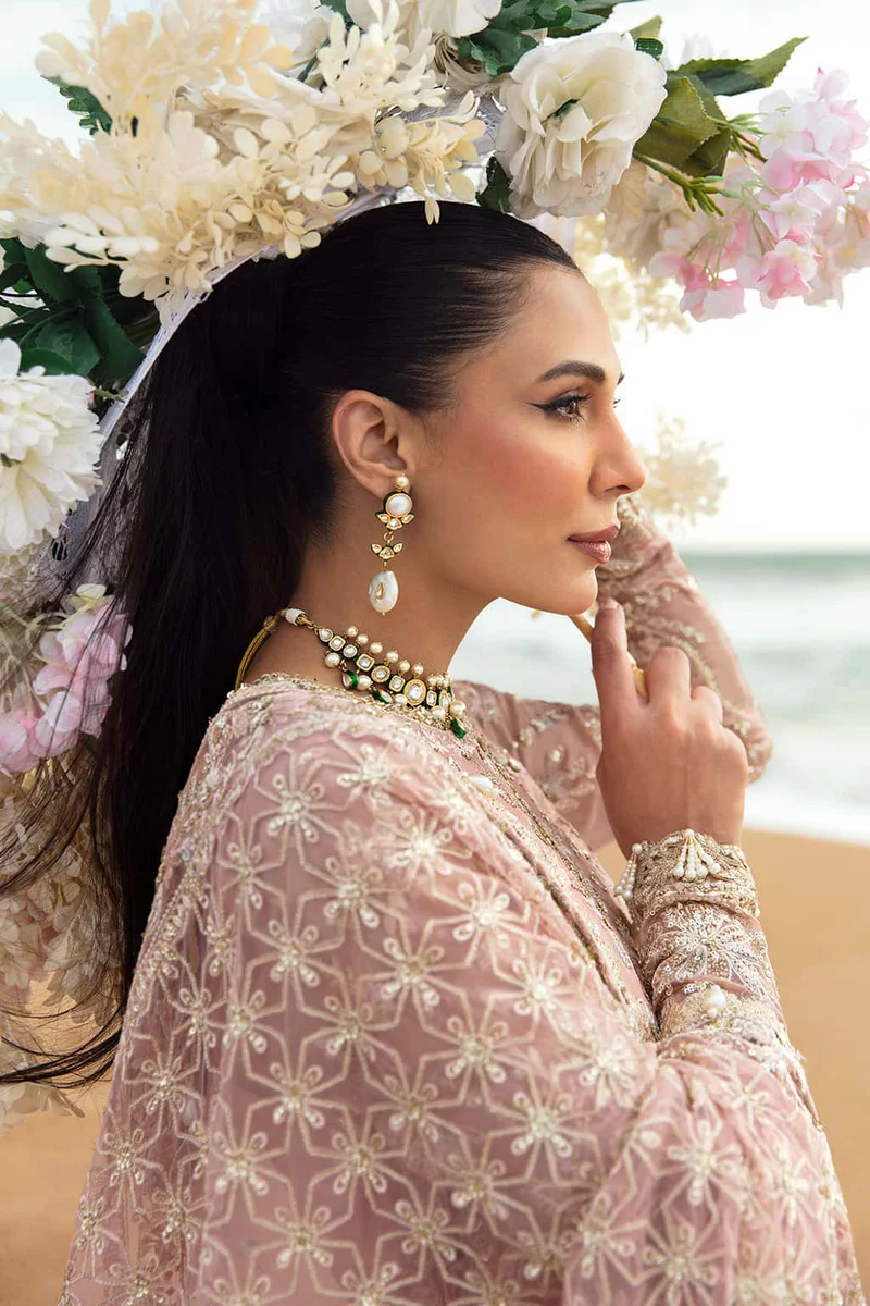 Model wearing pastel pink festive outfit by the beach